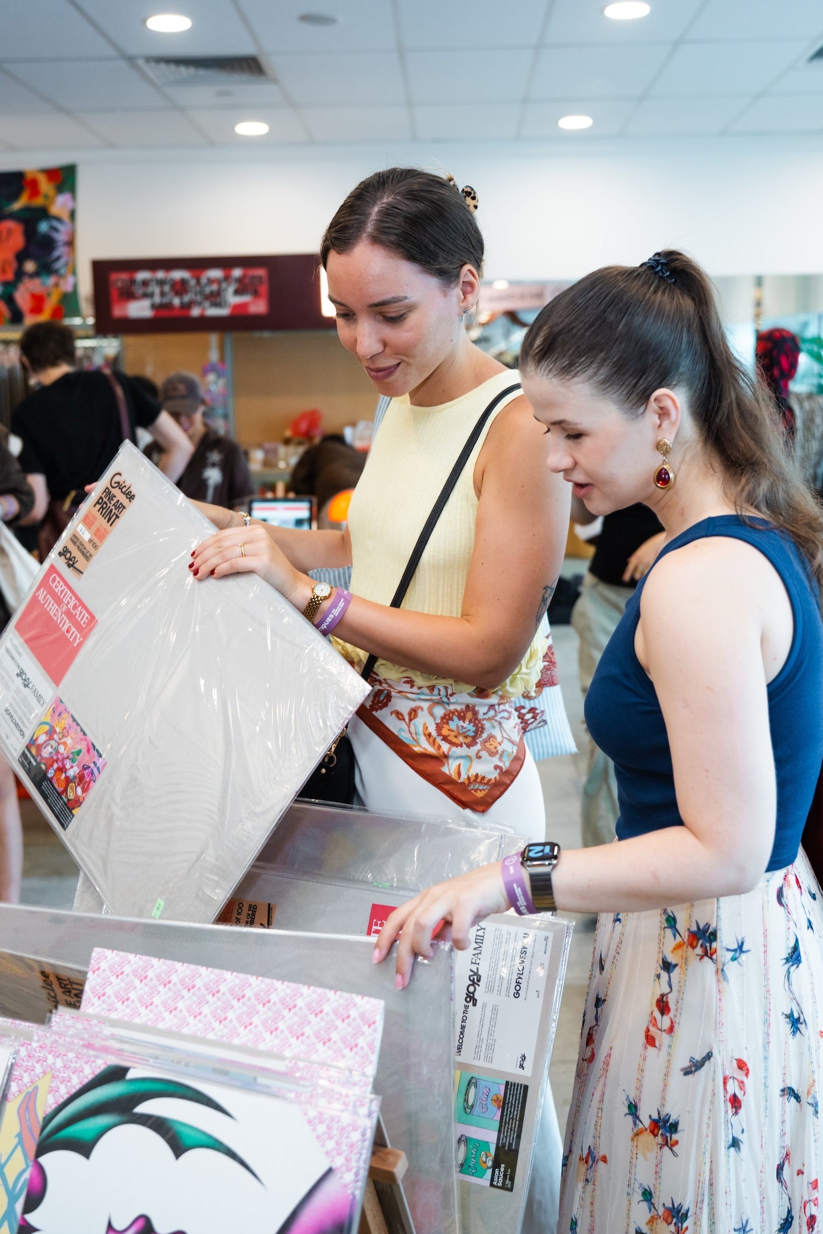 Two shoppers browsing art prints at Boutiques Singapore fair